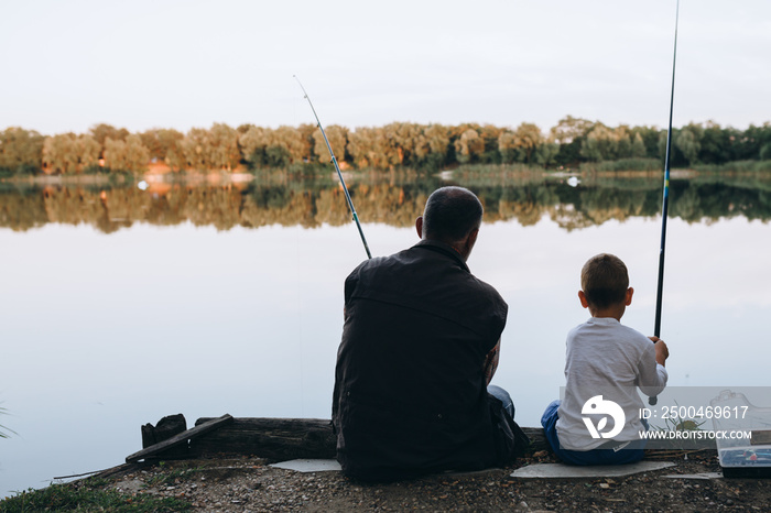 boy fishing with his grandfather outdoors at the lake