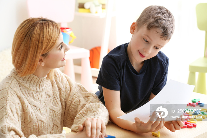 Female psychologist working with boy suffering from autistic disorder