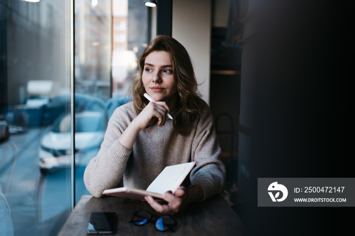 Pensive woman thinking about ideas with notebook at table