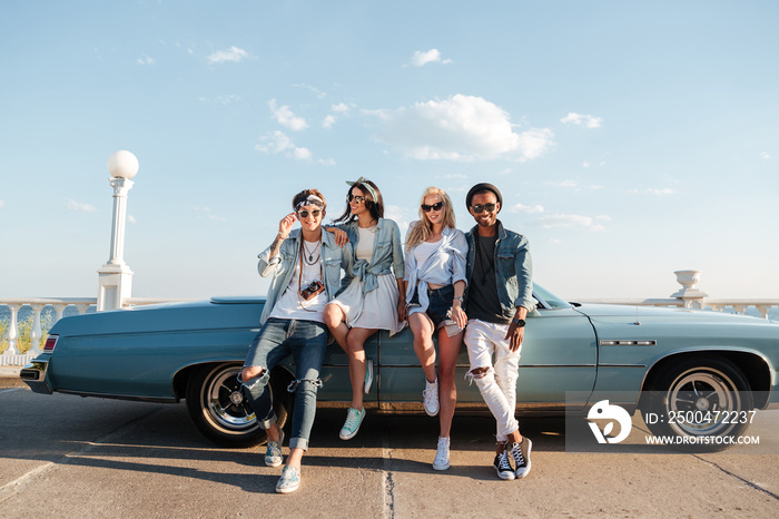 Happy friends standing near vintage car