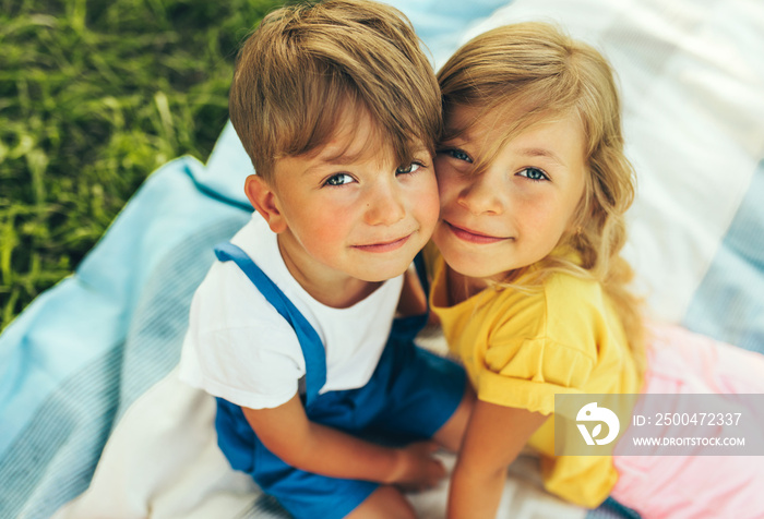 Outdoors close up portrait of smiling two children playing on the blanket outdoors. Little boy and c