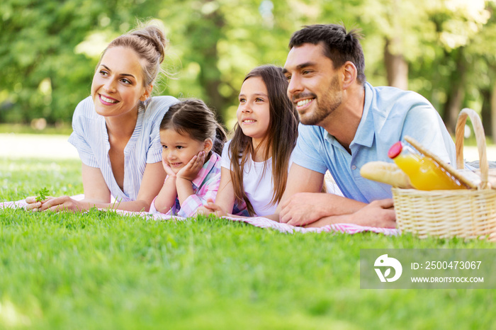 family, leisure and people concept - happy mother, father and two daughters laying on picnic blanket