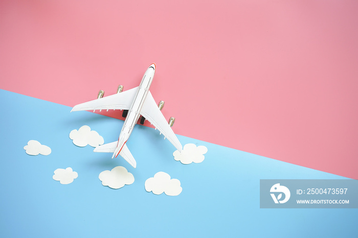平面设计的旅行概念，蓝色和粉色背景上有平面和云朵，带有复制空间。
