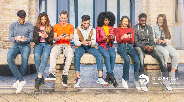 People from different cultures and country using smartphone together sitting on a bench. Youth using