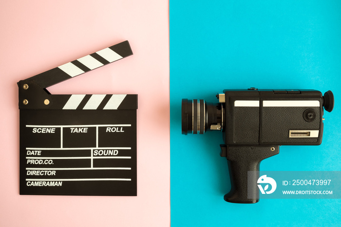 Clapperboard and vintage video camera on multicolored background.