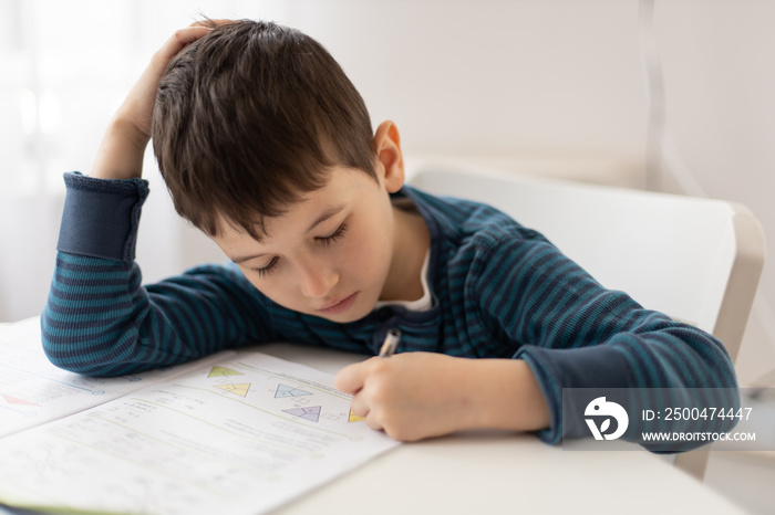 Portrait of young boy struggling with his homework at home. Children home education concept. Distanc