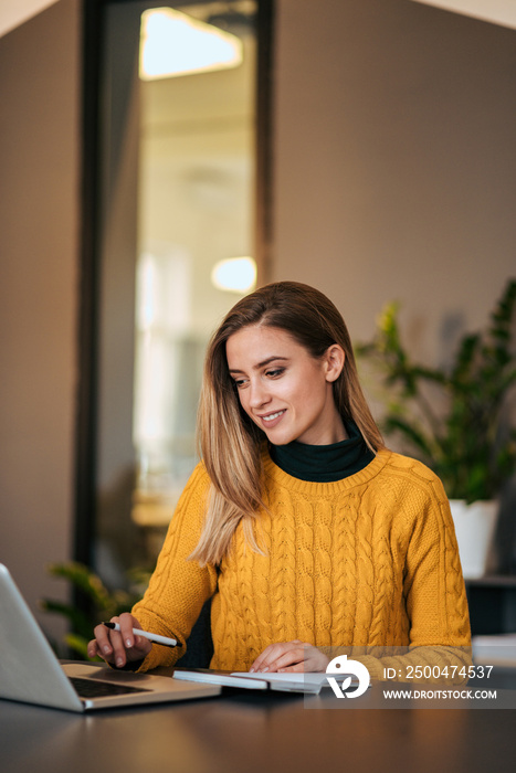 Casual business woman working with laptop and notebook.