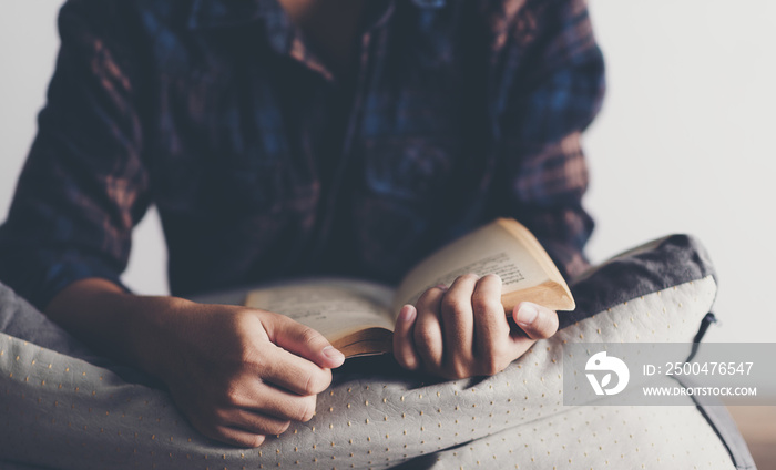 Young man is sitting on table and reading a book