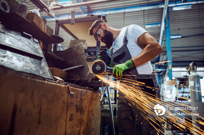 A heavy industry worker cutting metal parts with a metal cutter.