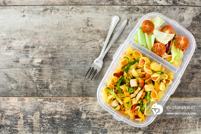 Lunch box with healthy food ready to eat.`Pasta salad on wooden table. Top view. Copyspace