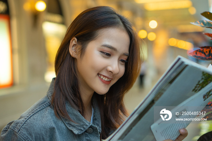 Beautiful Asian girl reading a magazine in the street