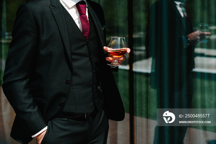 Close up of man hold glass of whiskey, drink alcoholic beverage in the pub. Business man drinking br