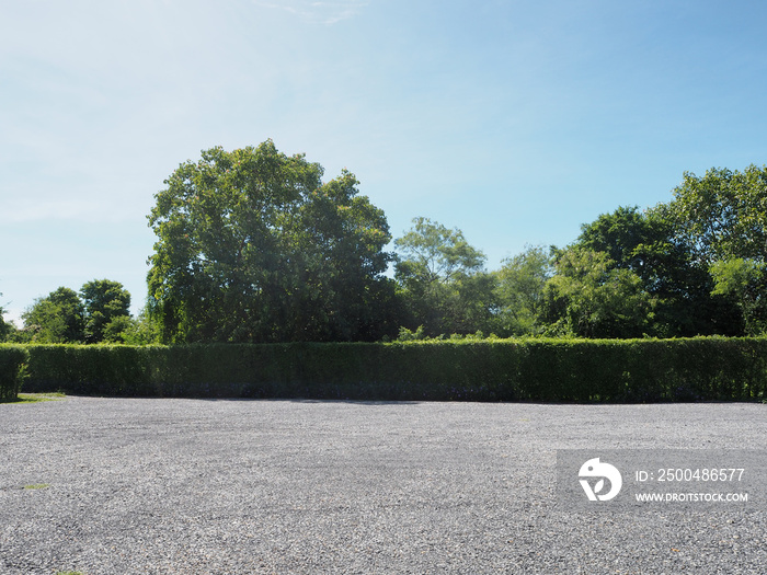 Parking lot sprinkled with gravel bush green tree blue sky nature background