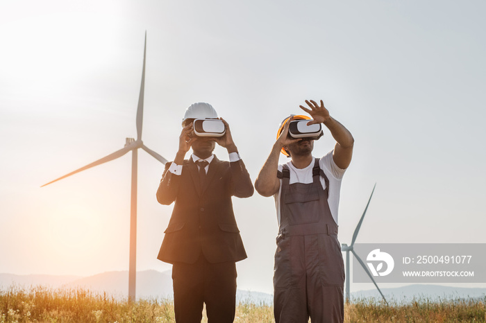 African american businessman and indian engineer wearing VR headset during meeting on farm with wind