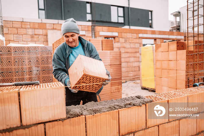 Professional worker building house walls with bricks and masonry details. People on construction sit