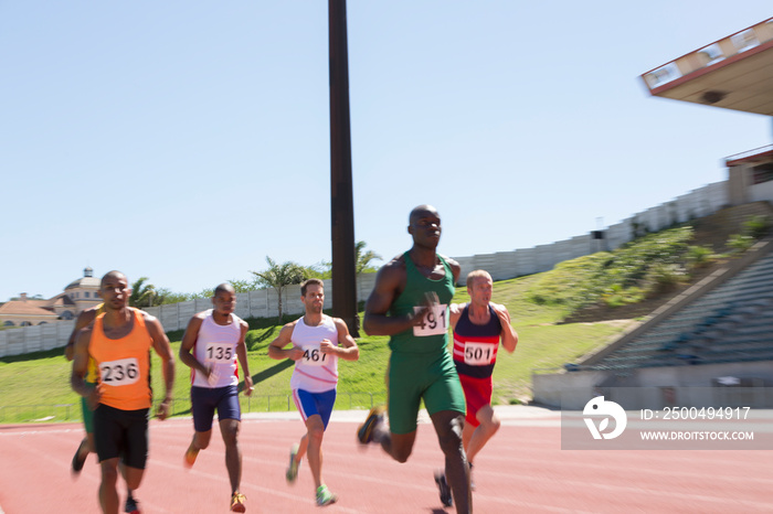 Male track and field athlete racing on sunny running track