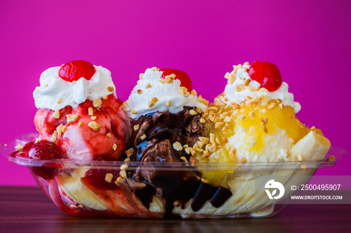 Banana split ice cream with cherries on top against pink wall