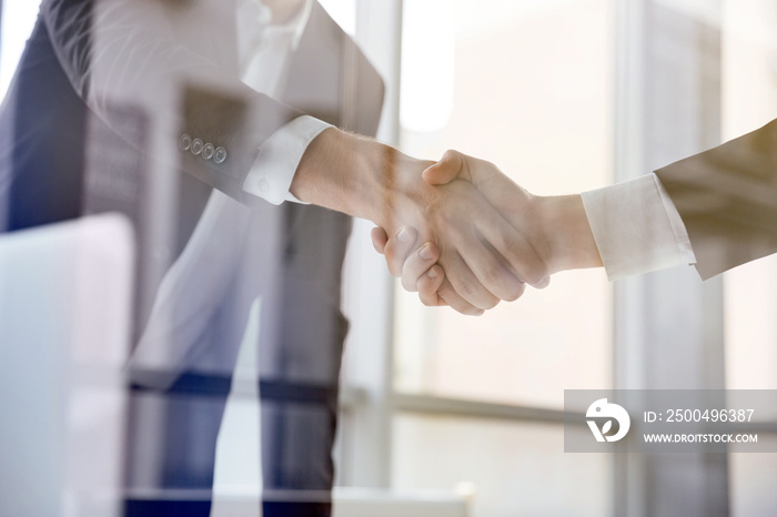 Two businessmen standing and shaking hands in office