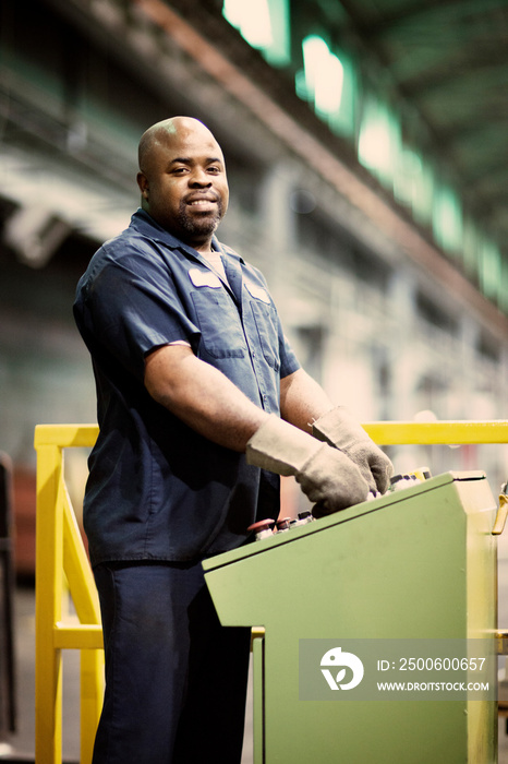 Smiling mature worker using machinery in factory