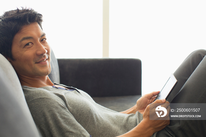 Portrait smiling man using digital tablet on sofa