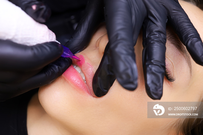 the master works performs permanent makeup of the upper lip of the model