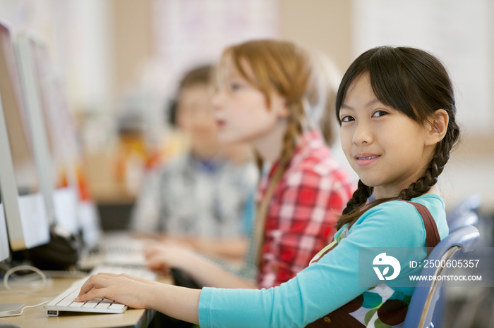 Asian, elementary student keyboarding on desktop computer