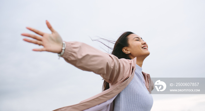 Asian woman enjoying nature standing with open arms