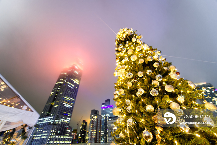 Christmas tree at night with New York City skyscrapers on background