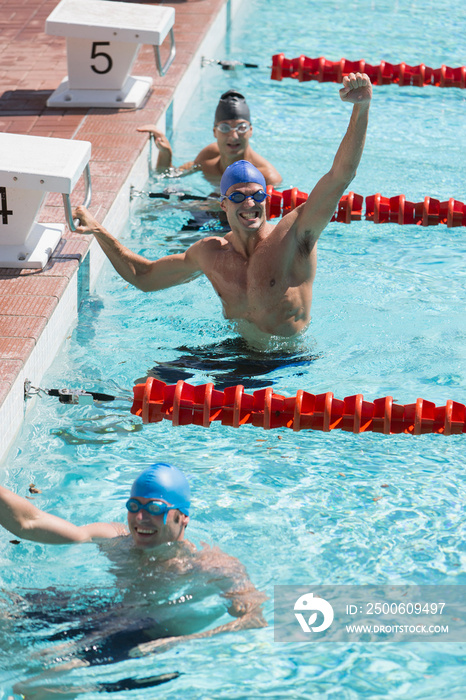 Confident male swimmer cheering and celebrating in swimming pool