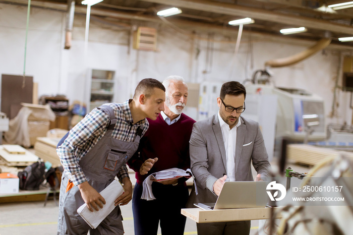 Three men standing and discuss in furniture factory