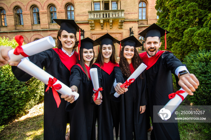 毕业快乐。5名毕业生在大学里手里拿着他的研究生文凭