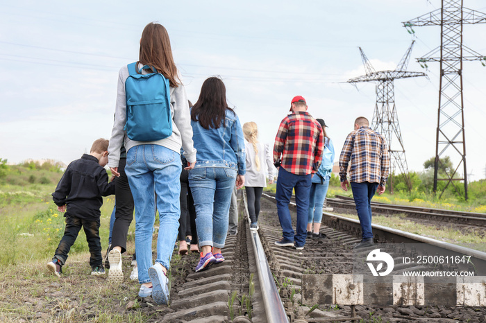 Group of illegal migrants walking along railway tracks