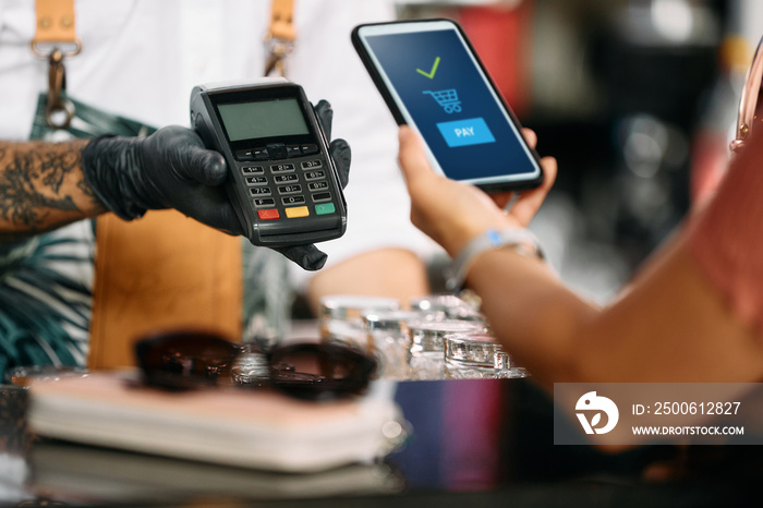 Close-up of woman makes contactless payment with smart phone in bar.