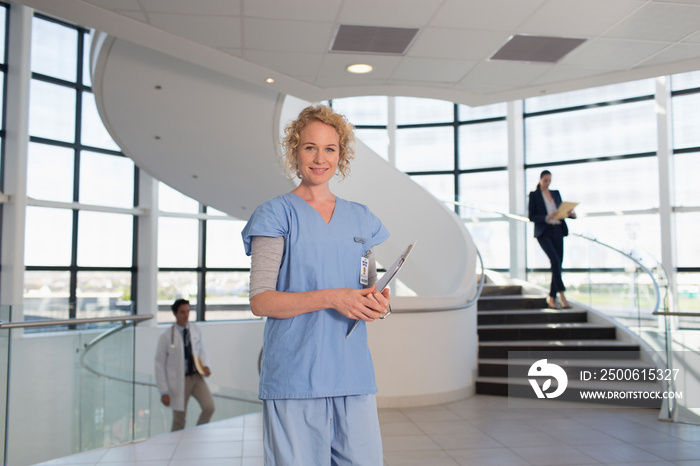 Portrait confident female nurse in modern hospital corridor