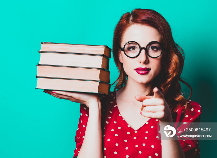 Portrait of redhead woman with books on blue background