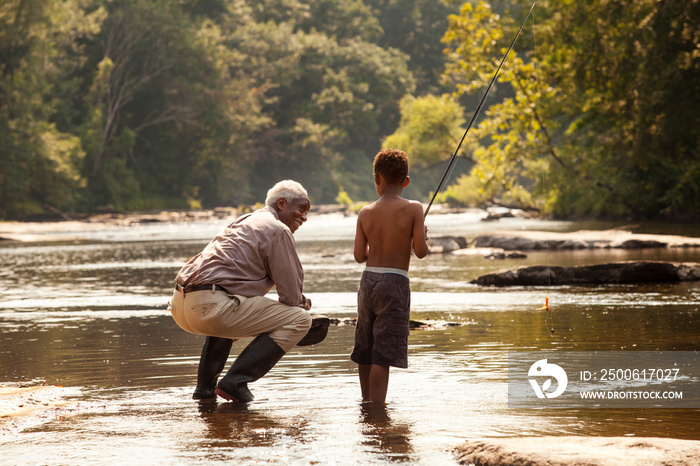 Boy and grandfather fishing in river