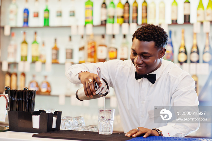 African american bartender at bar with shaker. Alcoholic beverage preparation.