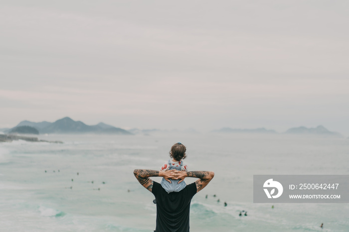 Father and daughter looking at the ocean and the mountains from above