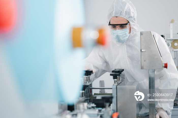 穿着防护服的科学家在一家工业实验室检查口罩制造机器
