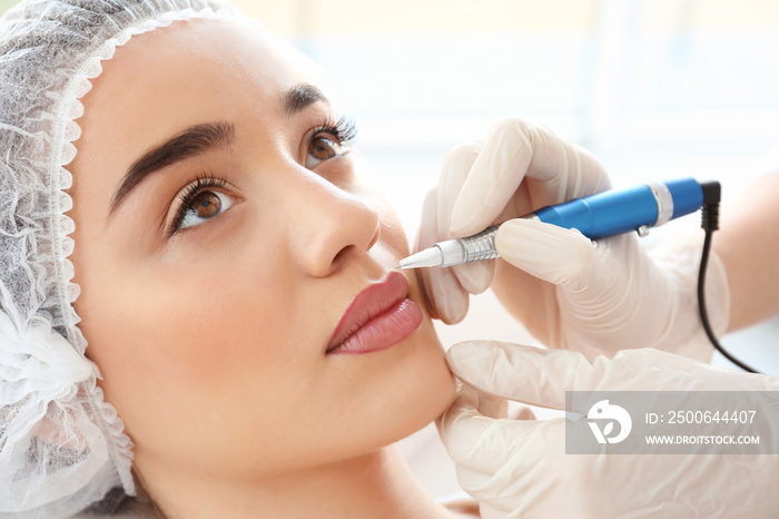 Young woman having permanent makeup on lips in beautician salon