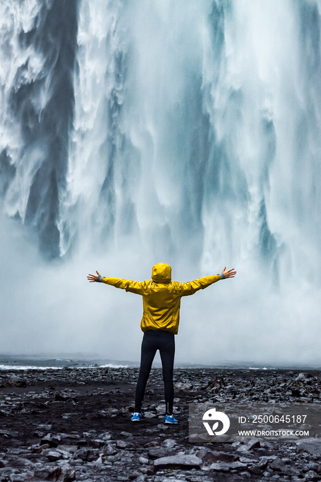 A person admirnig the beauty of Skogafoss waterfall located in Iceland