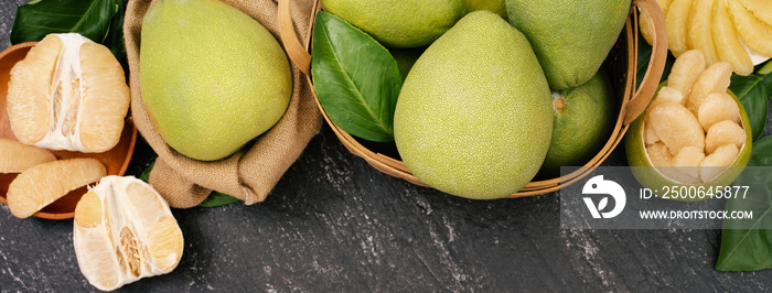 Fresh peeled pomelo, pummelo, grapefruit, shaddock on dark background in bamboo basket. Autumn seaso