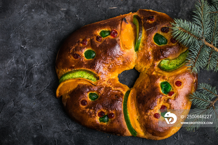 Rosca de reyes, spanish three kings cake eaten on epiphany day, on a gray rustic table