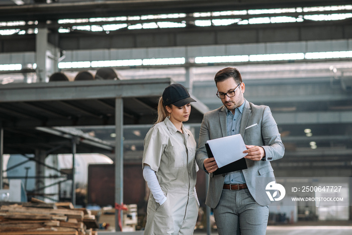 Manager discussing business with female factory employee.