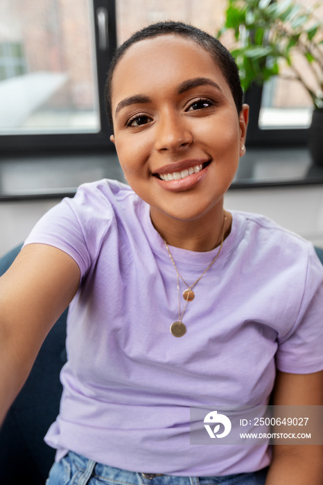 technology and people concept - happy smiling african american woman with taking selfie sitting in c