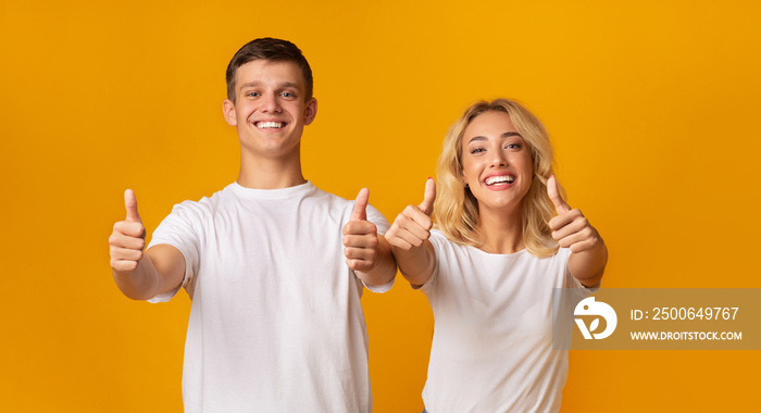 Smiling youngsters showing thumbs up gesture and looking at camera