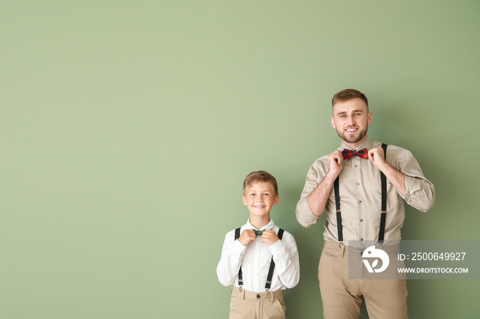 Portrait of fashionable father and son on color background