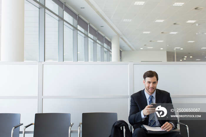 Portrait confident businessman using smart phone in office lobby