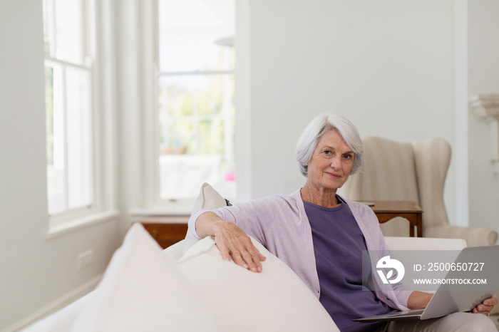 Portrait senior woman with laptop on sofa