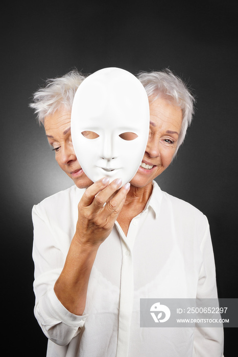 older woman hiding happy and sad face behind mask, concept for manic depression or bipolar or dramed